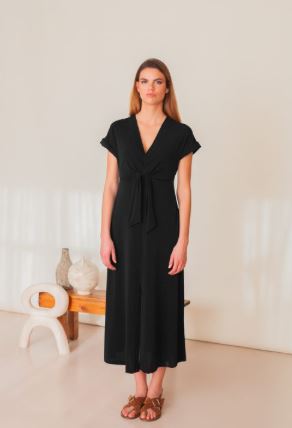 Mujer vistiendo vestido negro de escote en pico y detalle de nudo en la cintura.