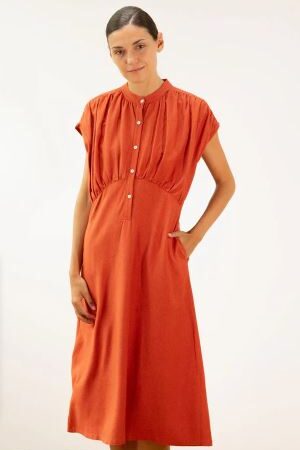Mujer vistiendo vestido midi de color caldera, cuello mao, botones y bolsillos